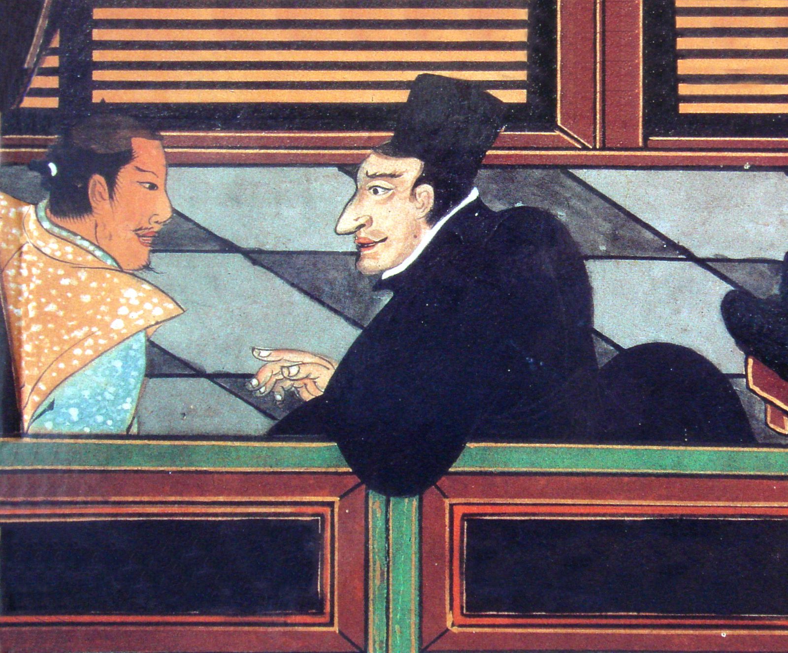 A black-robed Jesuit leans over a balustrade, one hand raised, talking with the Japanese man beside him, in a nanban folding-screen detail of about 1600