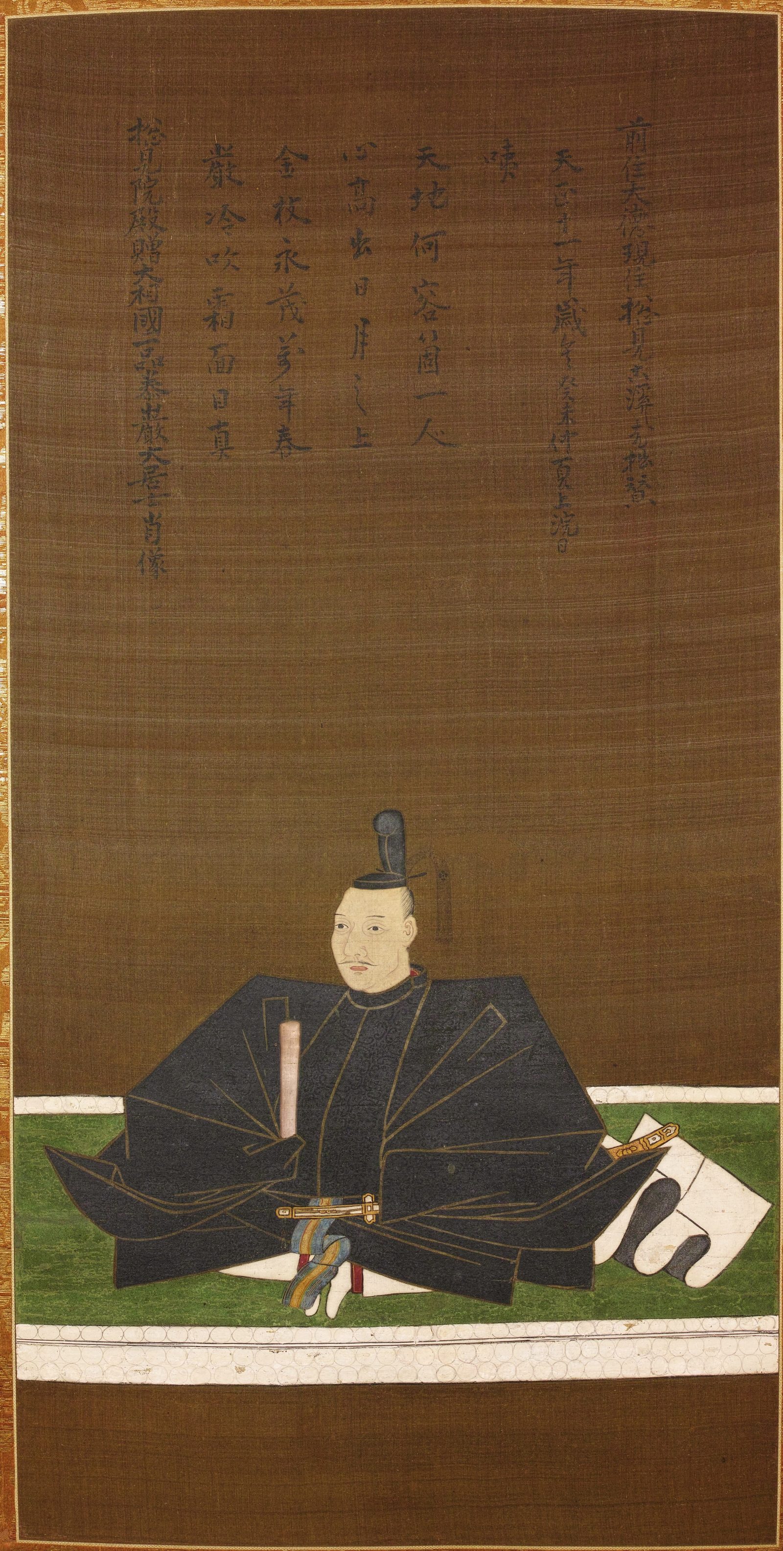 Memorial portrait of Oda Nobunaga, c. 1583: seated on a mat in black court robes and cap, a baton in hand and a sword at his side, beneath a long inscription